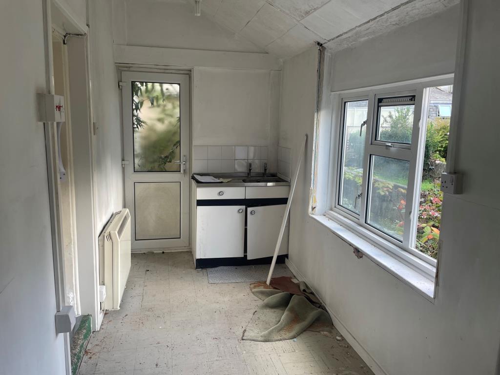 Lot: 102 - HOUSE FOR IMPROVEMENT - Kitchen with wash basin unit and door leading to rear